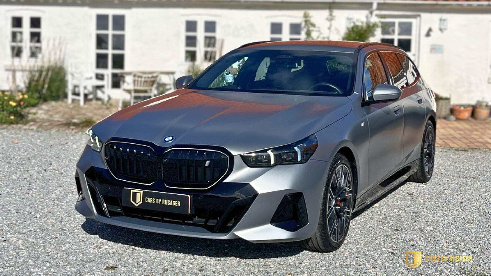 Grå BMW i5 Touring med mat lak fotograferet skråt forfra foran Cars by Riisager.