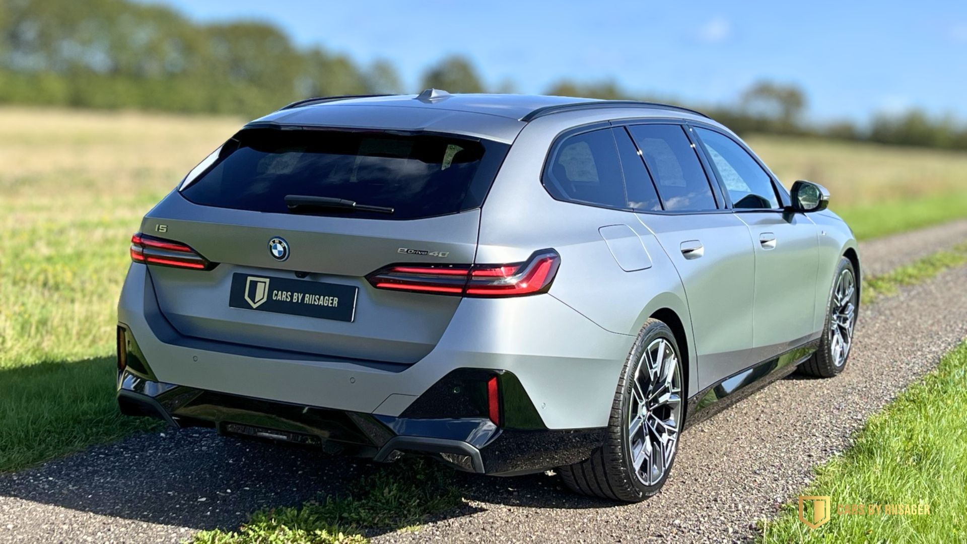BMW i5 Touring fotograferet skråt bagfra på en landevej.