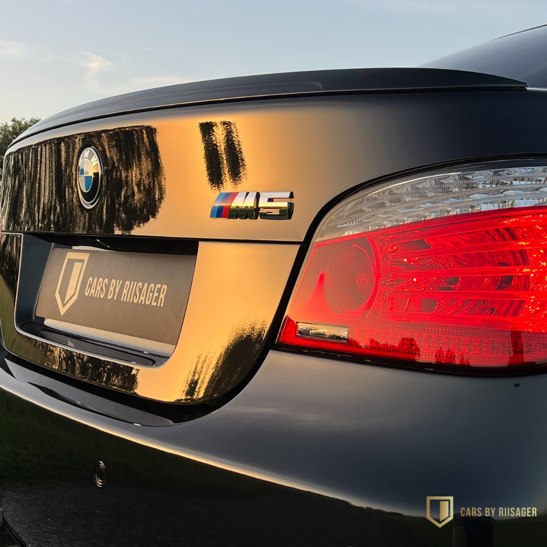 bmw-m5-e60-m-emblem-bagklap Nærbillede af BMW M5-emblem på bagklappen af en BMW M5 E60.