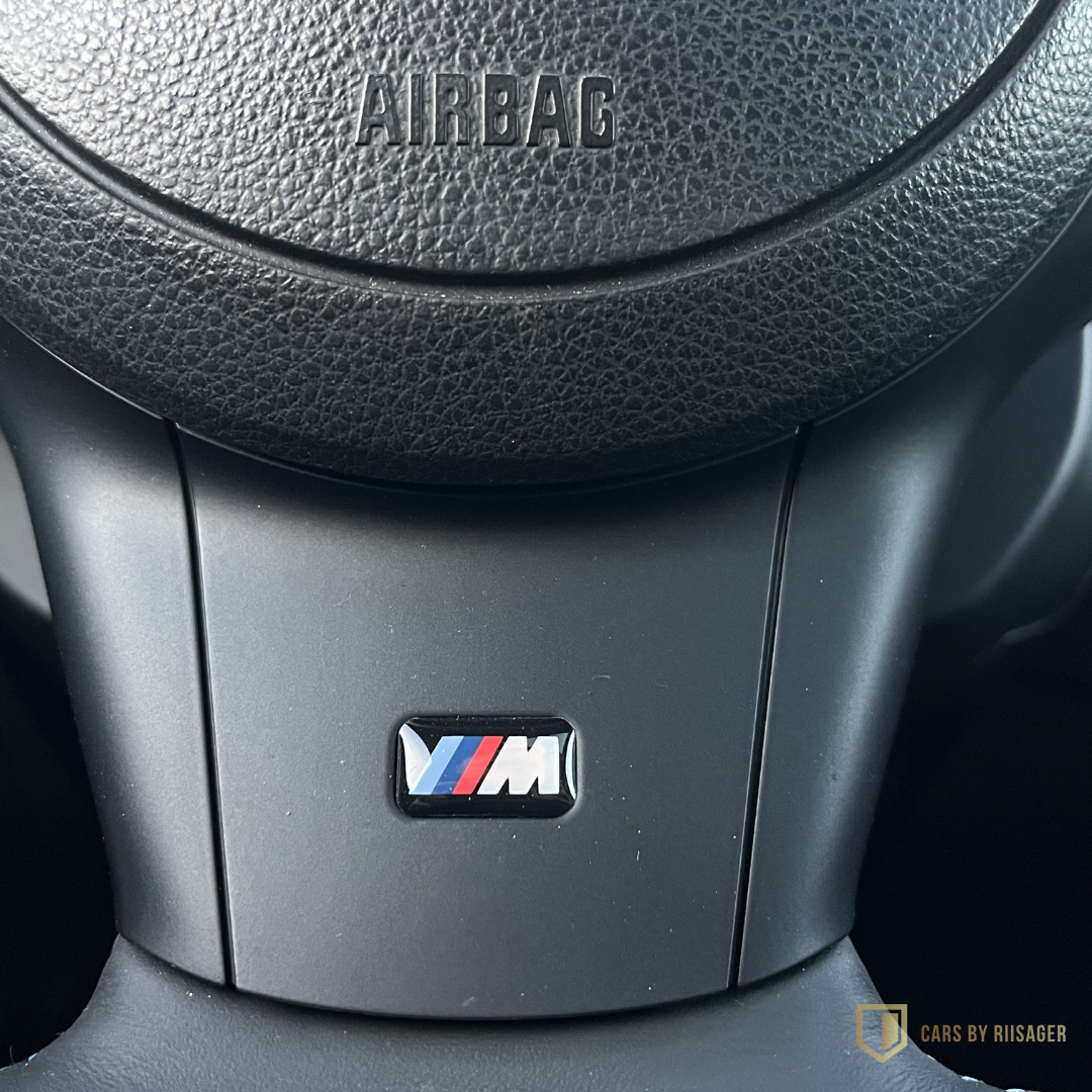 bmw-m5-e60-m-logo-rat M-logo i rattet på BMW M5 E60 – detalje fra den ikoniske sportslimousine med V10-motor.