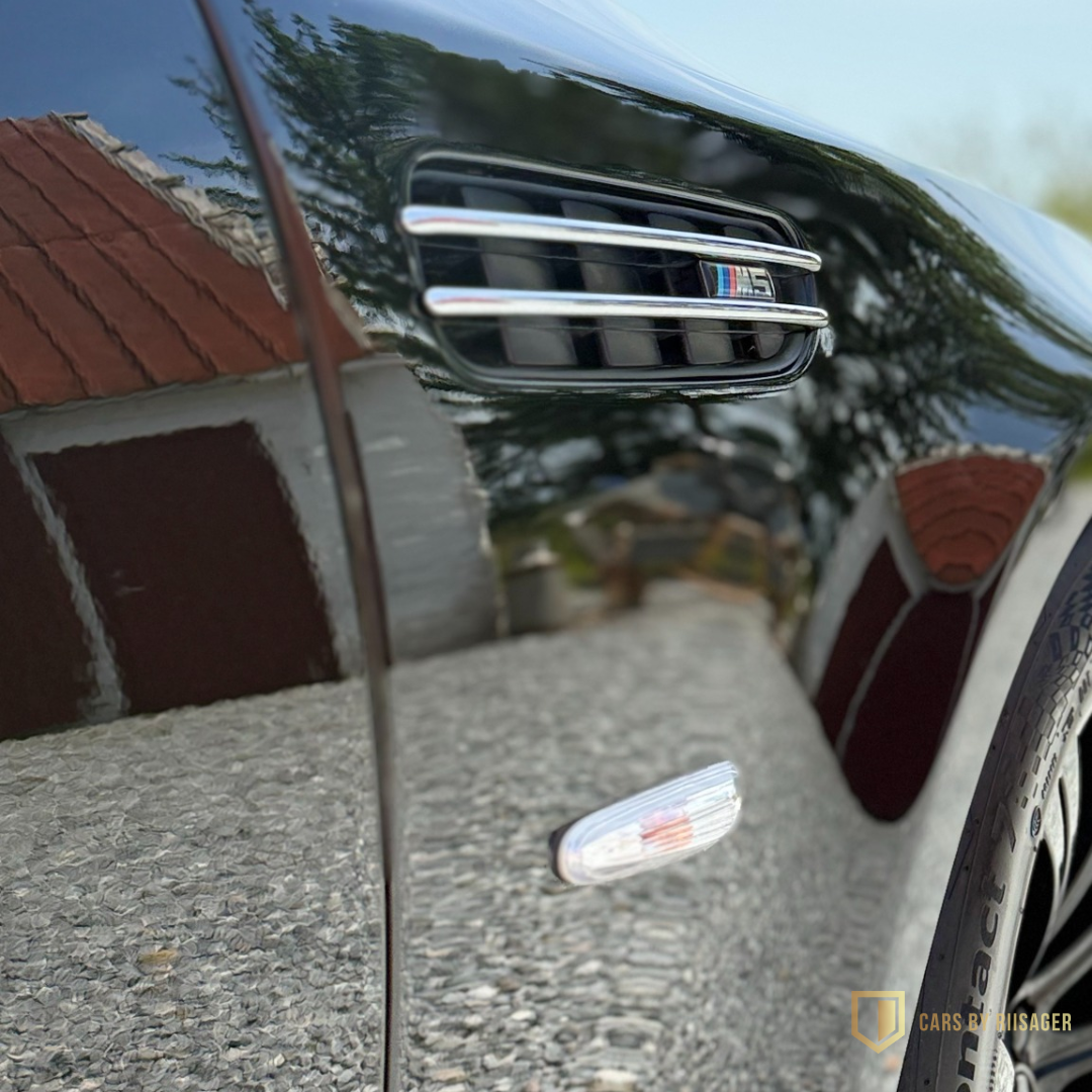 bmw-m5-e60-sidegill-m-logo Spejlblank sort lak på BMW M5 E60 med tydelige refleksioner efter lakkorrektion.